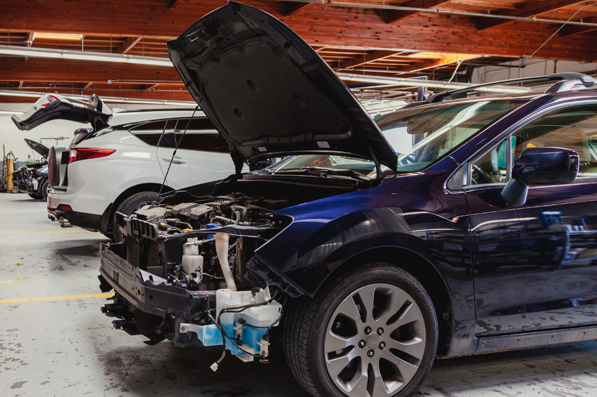 Auto body repairs. Mechanic worker burnish and polishing automobile car body by buffing grinding machine in garage workshop. Toned