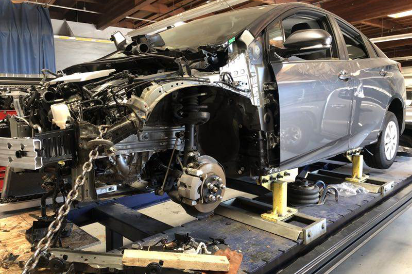 Auto body repairs. Repairman mechanic worker plastering automobile car body by plaster in garage workshop